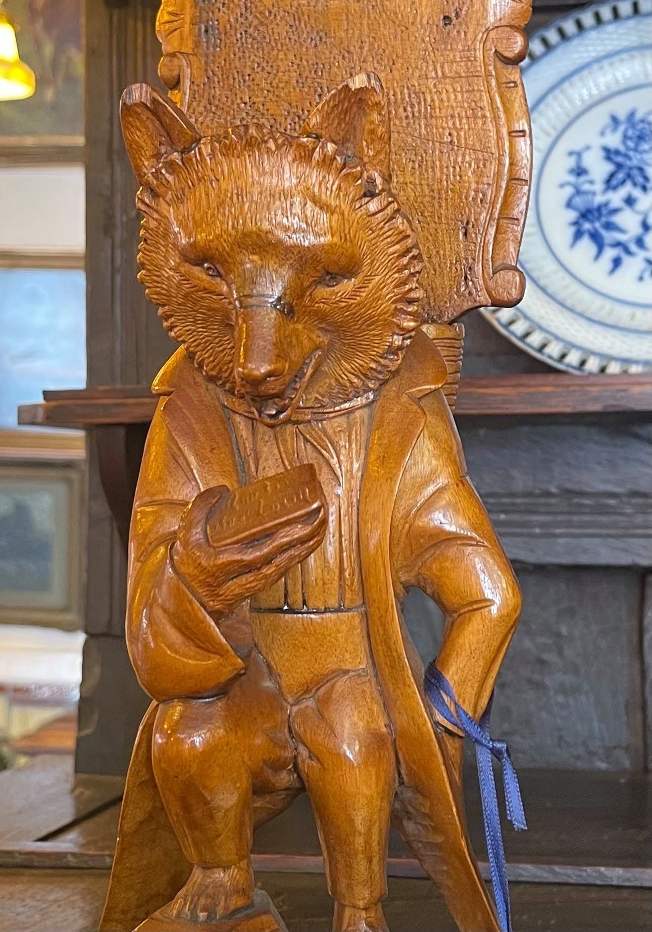 Wooden carved fox figure with a small sack, displayed indoors on a shelf