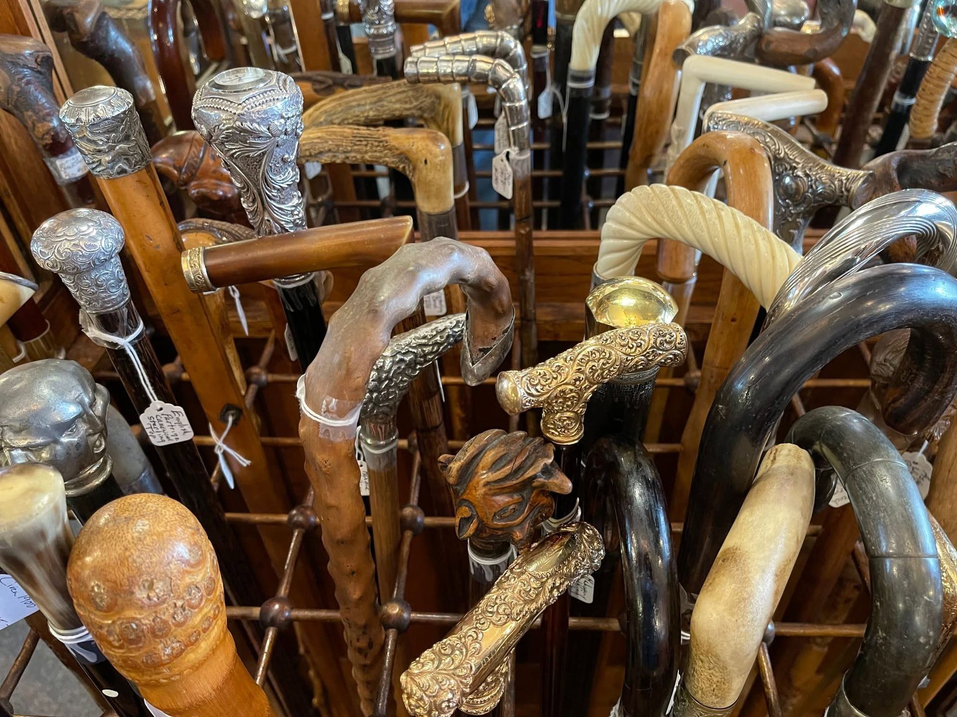 Row of ornate walking canes with carved, metallic and wooden handles in a shop display