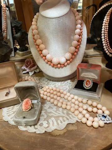 Pearl necklaces and coral jewelry displayed on a white bust in a vintage-style shop