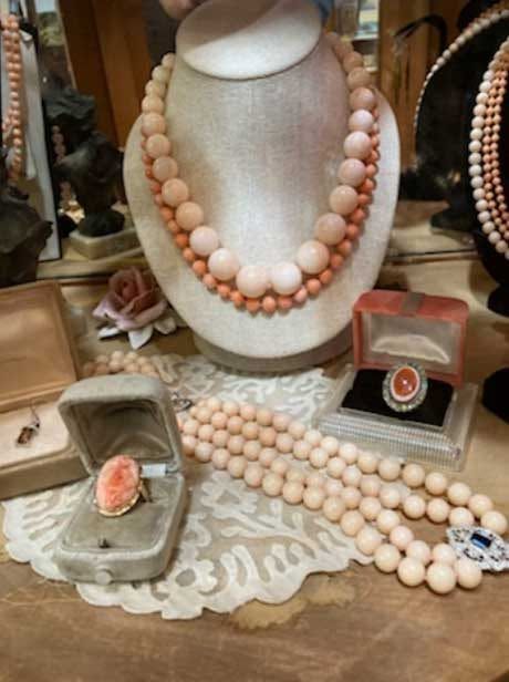 Pink beaded necklaces and matching rings displayed on a jewelry bust and velvet boxes
