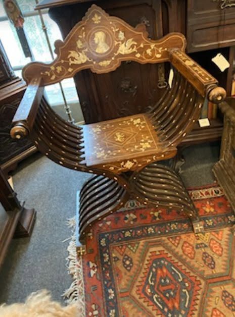 Ornate wooden chair with inlaid details and carved backrest on a patterned rug in a room