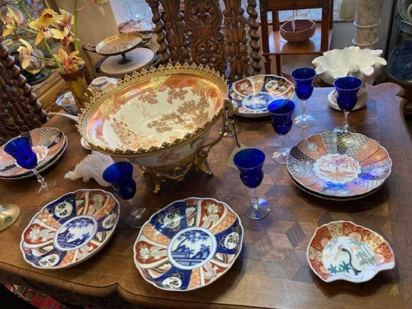 Decorative blue-and-white ceramic dishes and cups arranged on a dining table with flowers and a glass centerpiece