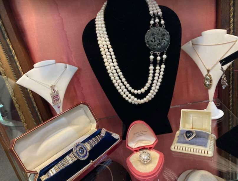 Jewelry display with pearl necklaces, rings, bracelets, and necklace stands in a showcase