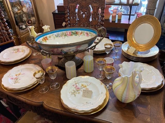 Elegant dining table set with floral china, glassware, serving bowl, and decorative plates