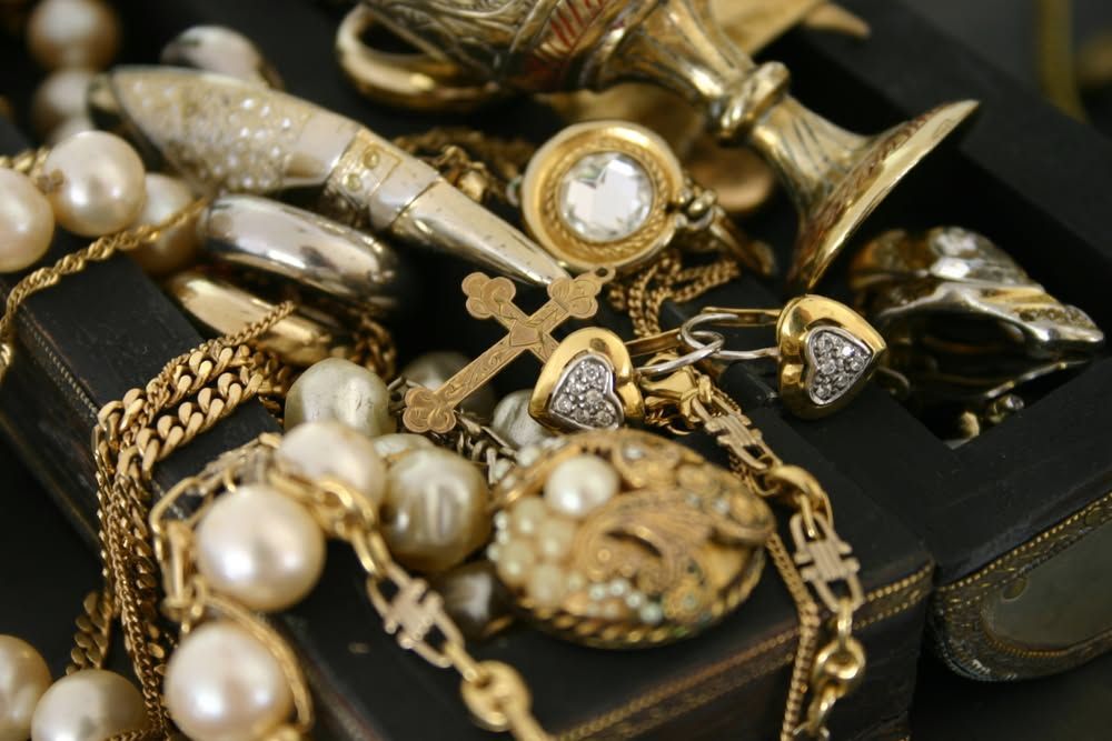 Gold and pearl jewelry pieces in a black box, including chains, rings, and earrings