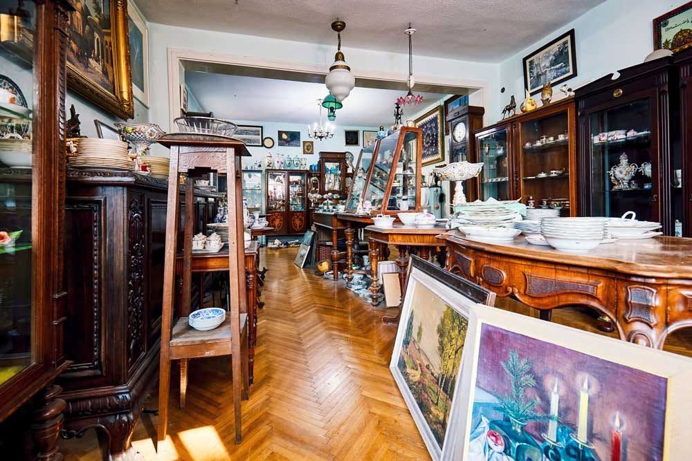 Antique shop interior with wooden cabinets, framed art, and glassware on shelves and tables