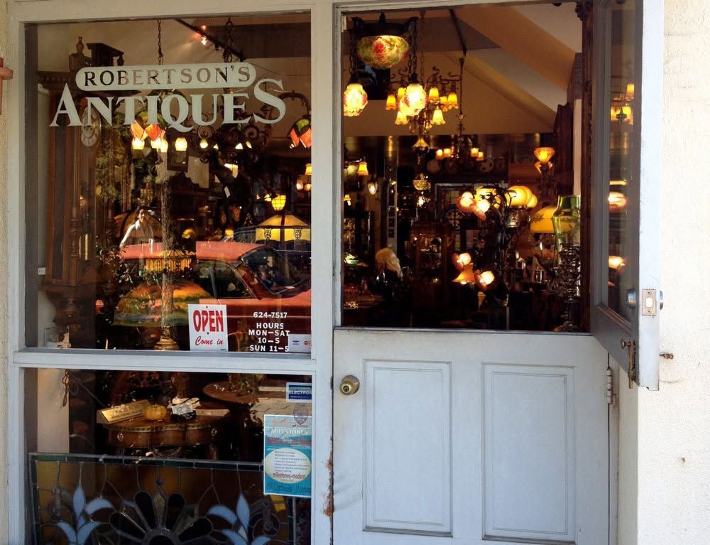 Antique shop entrance with glass door and window display of hanging lights and decor