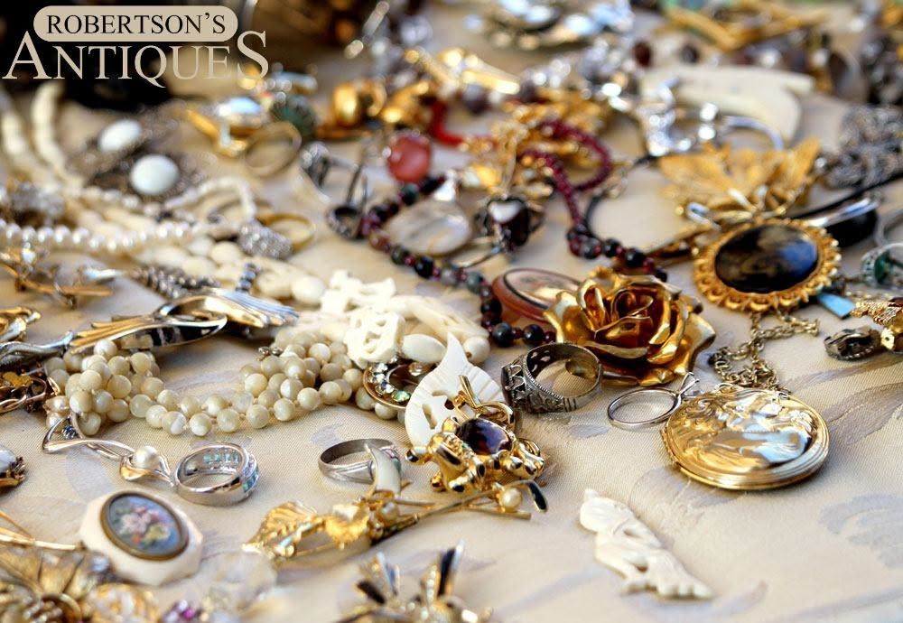 Assorted vintage jewelry and brooches displayed on a tabletop with a Robertson's Antiques watermark