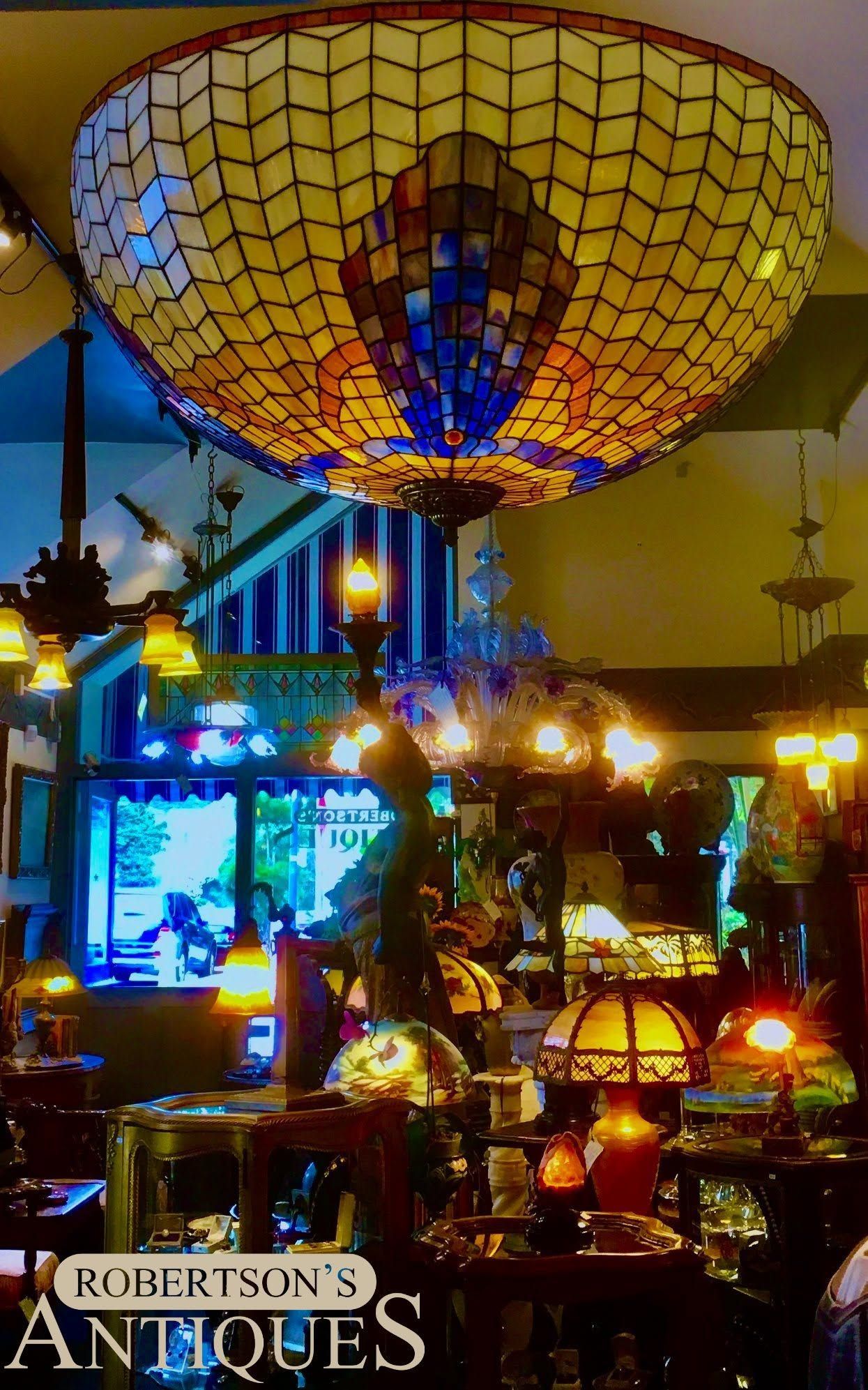 Warmly lit antique shop with colorful stained-glass lamps and a large mosaic ceiling lamp overhead