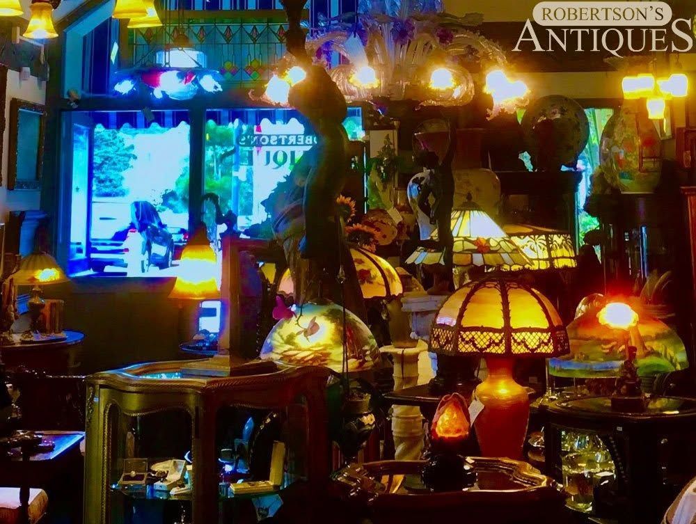 Warmly lit antique shop interior with lamps, stained glass, and a glowing window display