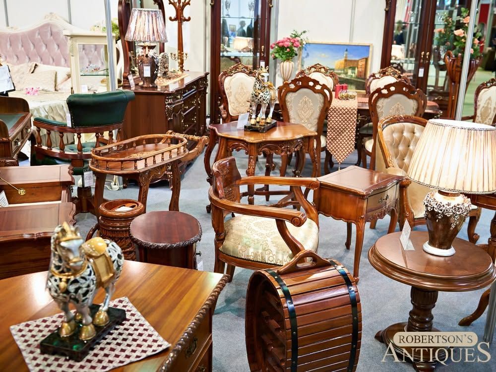 Antique furniture showroom with wooden chairs, small tables, lamps, and decorative pieces arranged in a crowded display