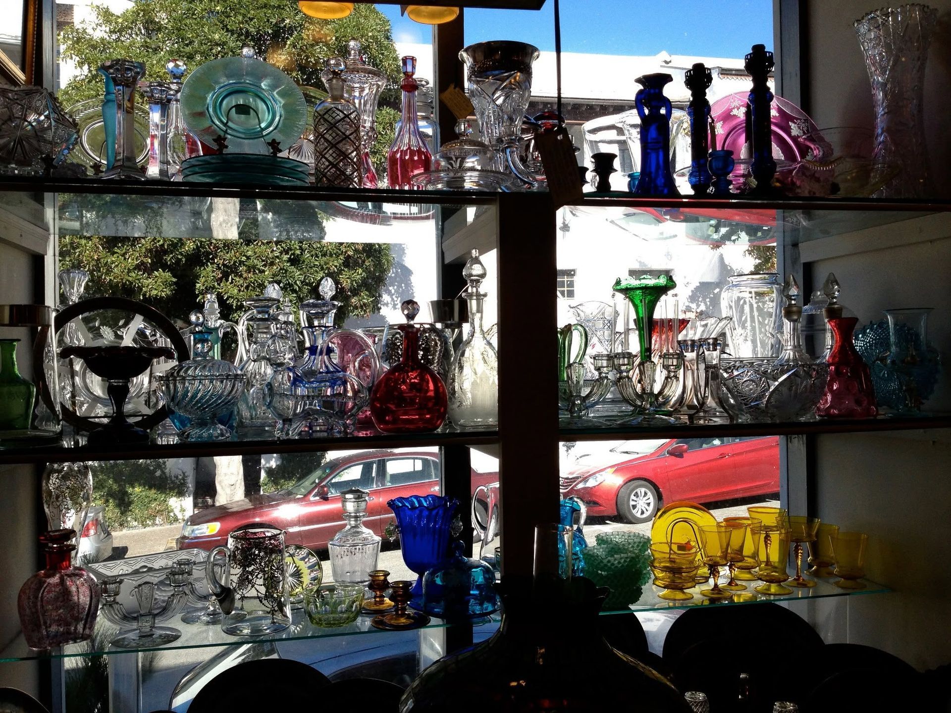Glass pipes and smoking accessories displayed on shelves in a shop, with cars visible outside.