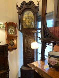 Antique grandfather clock and wall clocks in a warmly lit room with wood furniture