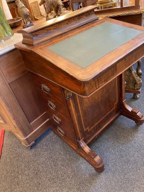 Wooden antique writing desk with green leather top and drawers in a shop