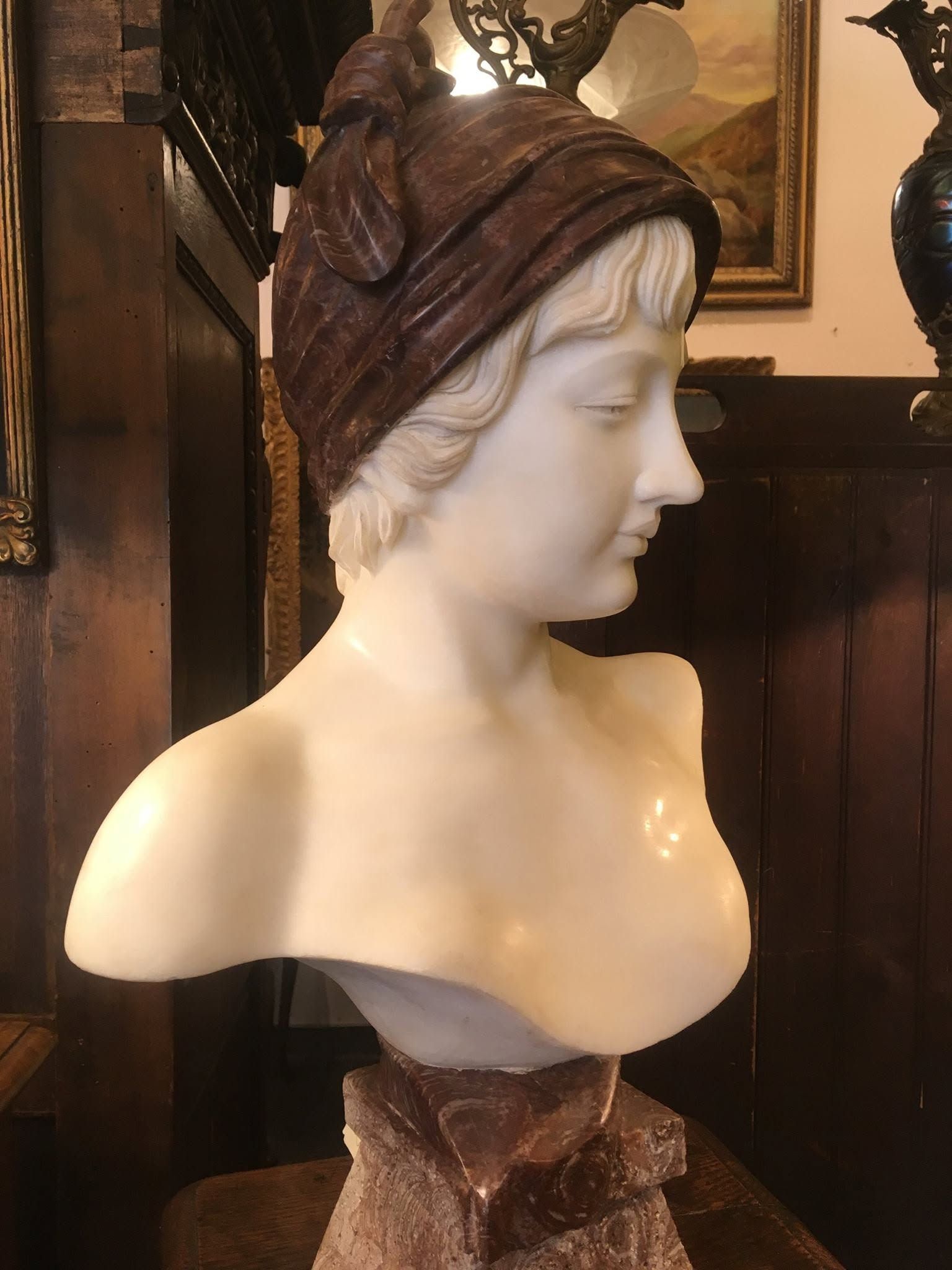 White bust sculpture of a woman wearing a dark headwrap in a dimly lit room