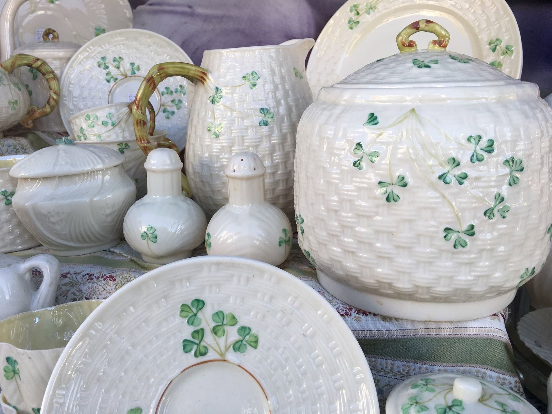 White ceramic tableware with green floral patterns displayed together on shelves