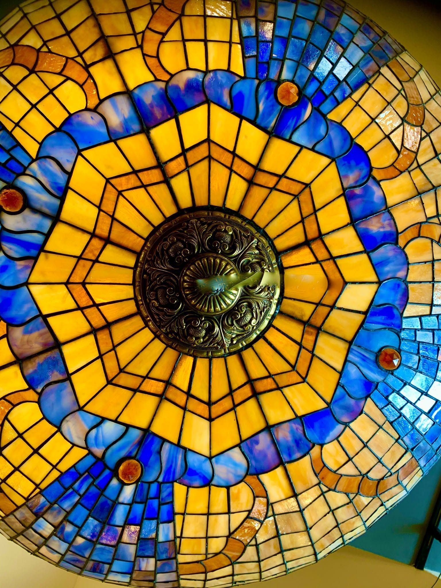 Colorful mosaic with a yellow sunburst pattern and blue ring around a central dark circle