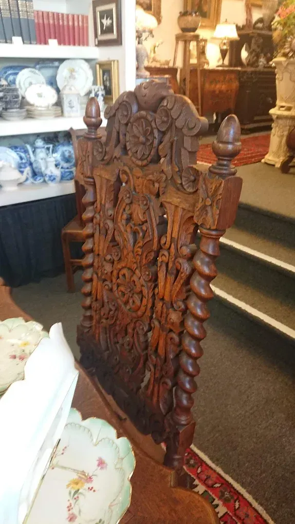 Ornate carved wooden chair with floral details in an antique shop interior
