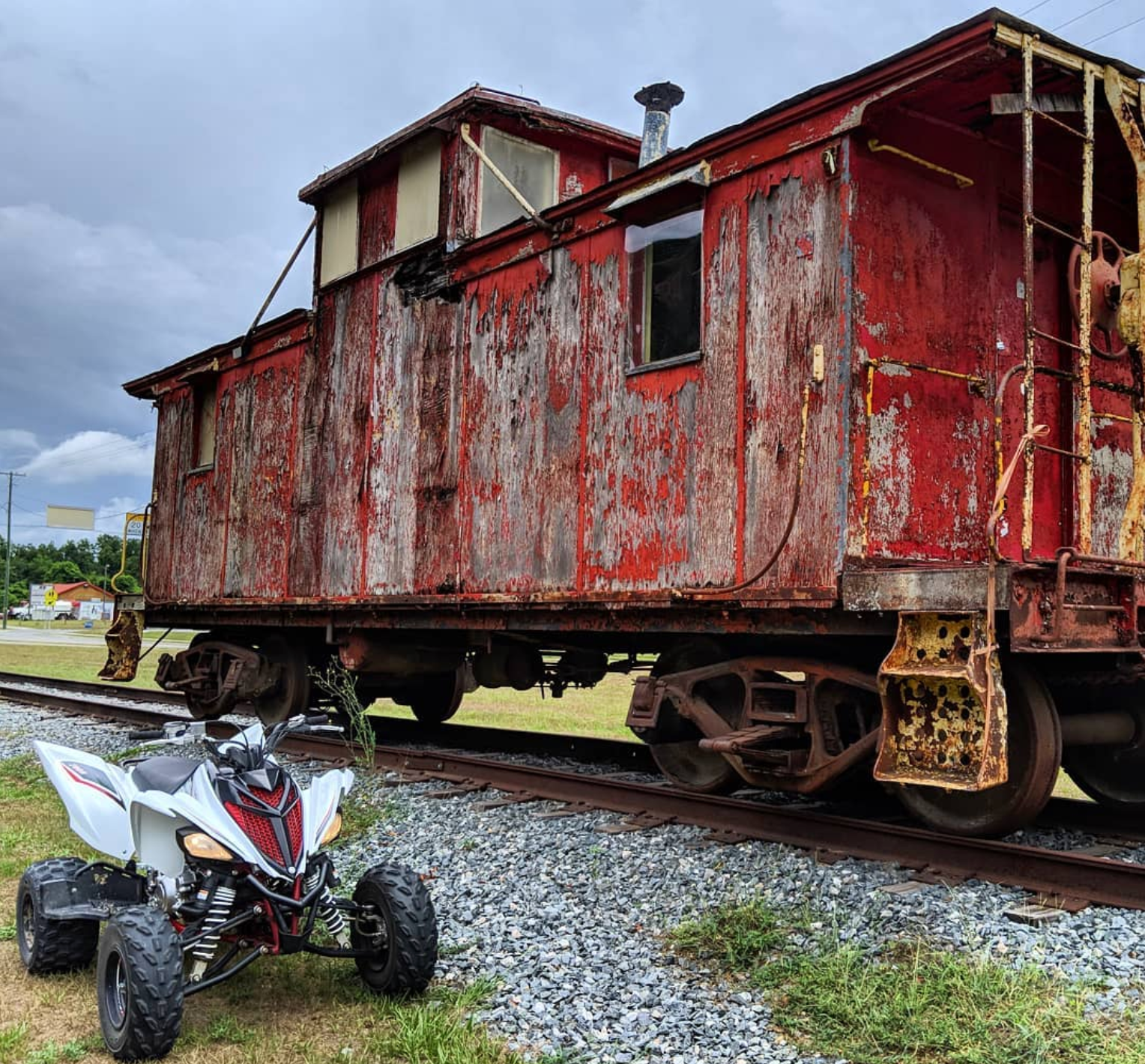 a red train car with a white atv parked in front of it