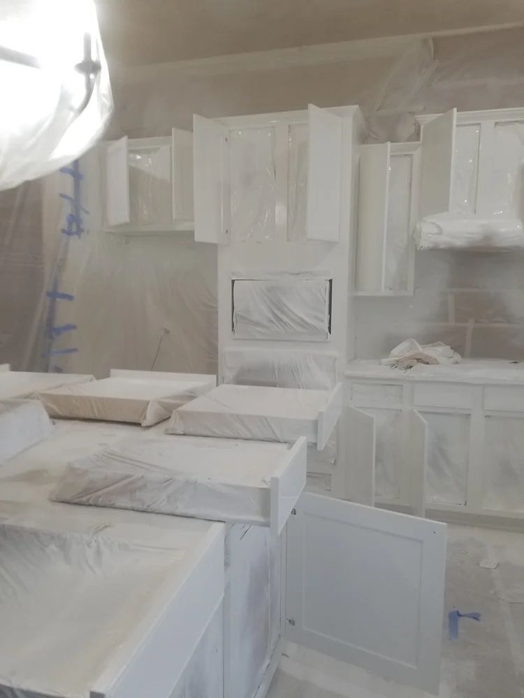 Kitchen cabinets covered in white paint, undergoing a painting project.