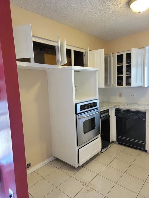 Kitchen with white cabinets, oven, dishwasher, and cream-colored walls and floor.