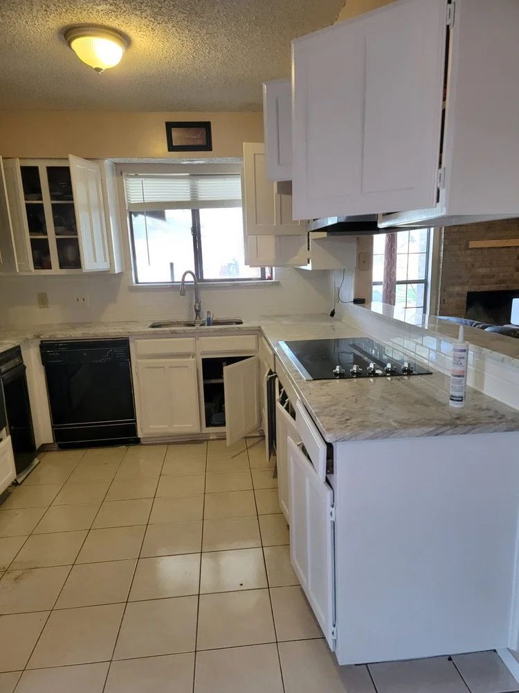White kitchen cabinets, granite countertops, black appliances, and tiled floor.