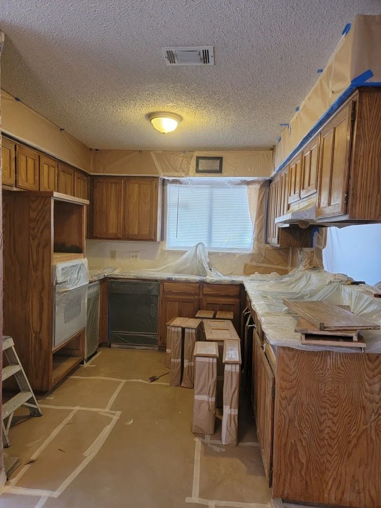 Kitchen under renovation with oak cabinets, appliances, and countertops covered in protective materials.