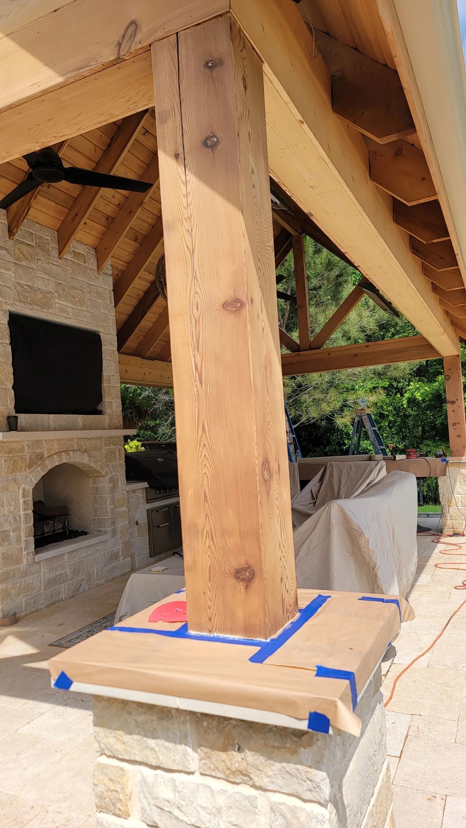 Wooden support beam on a stone pillar, part of an outdoor structure, with taped edges.