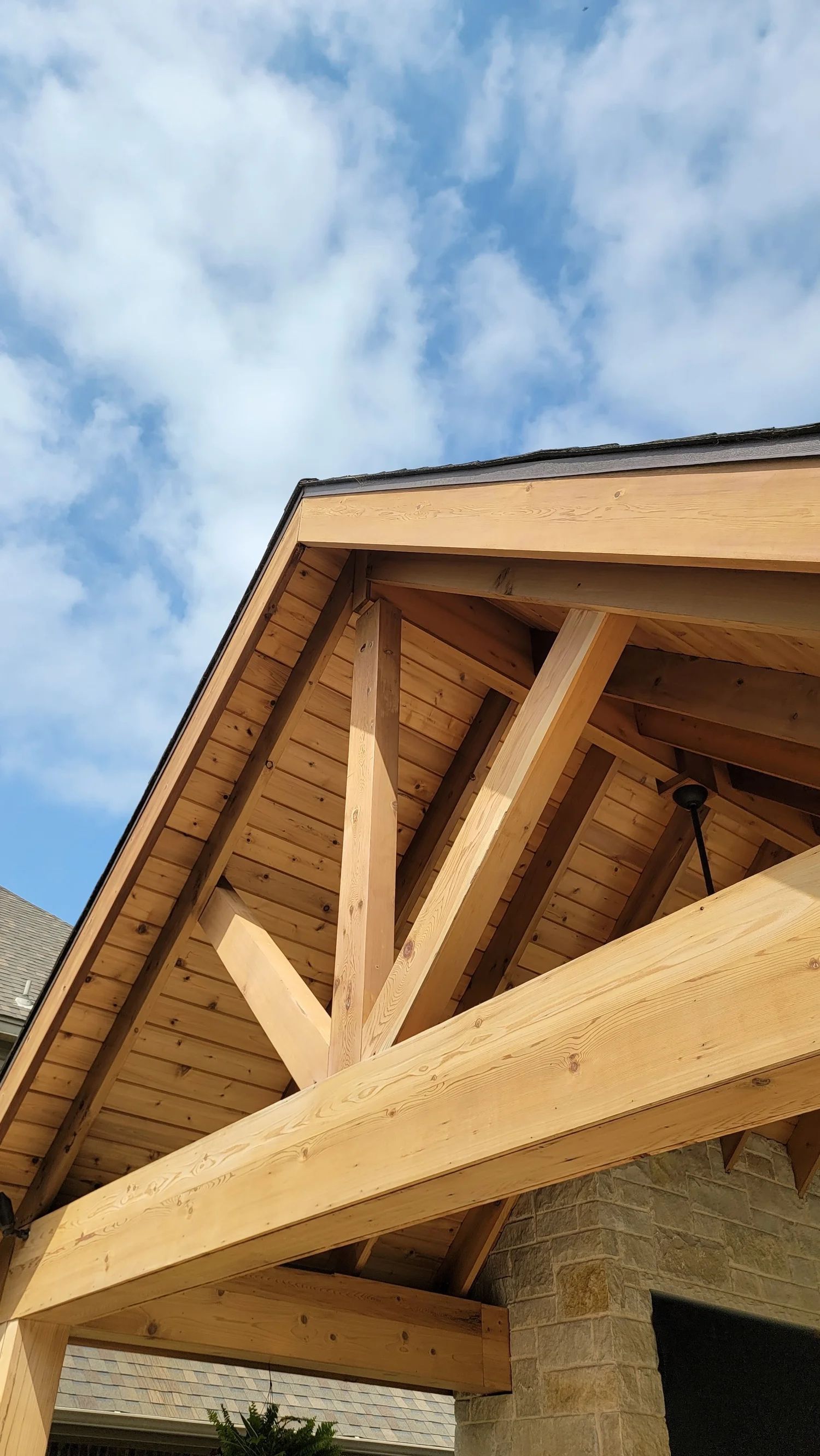 Wooden roof structure against a cloudy sky.