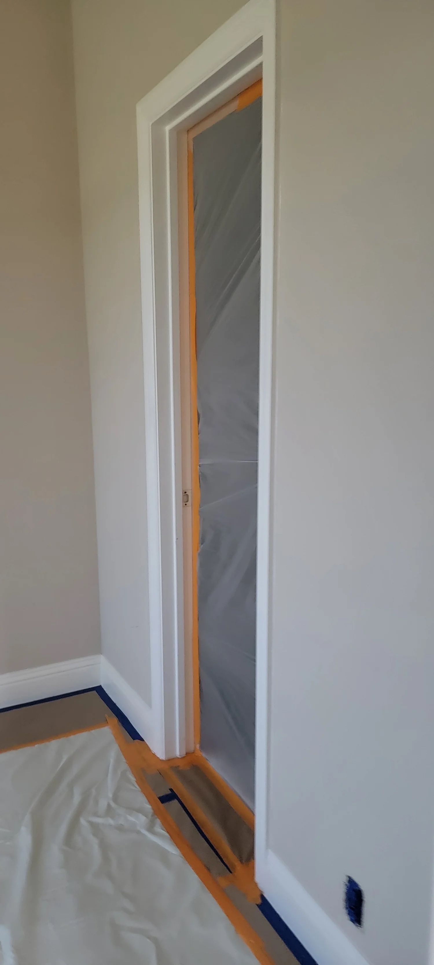 Narrow doorway with white trim; walls are light gray. Protective plastic covers the opening.