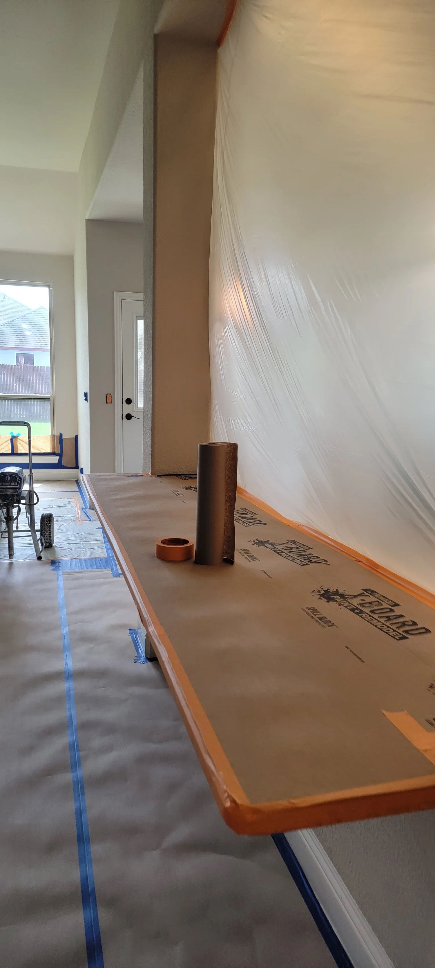 A long wooden counter with two cylindrical objects, in a room being worked on.