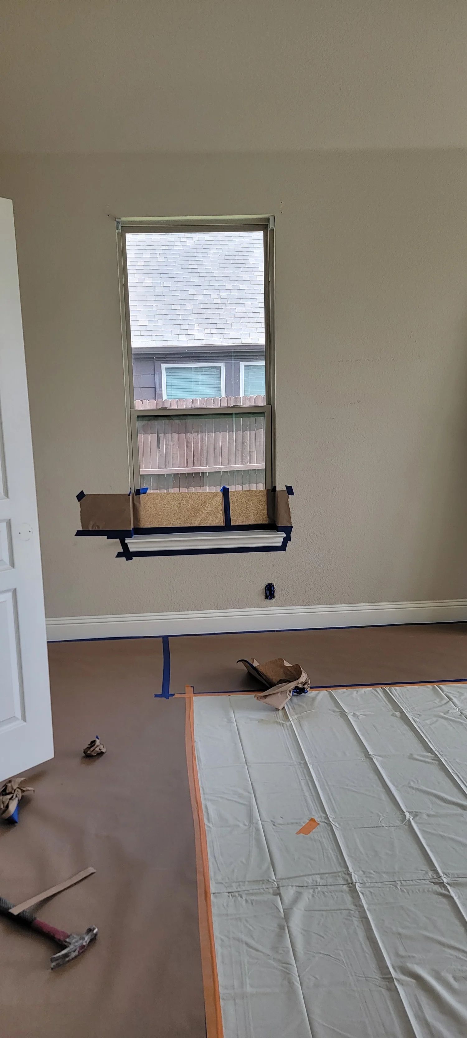Interior view of a room with a window, construction materials on the floor.