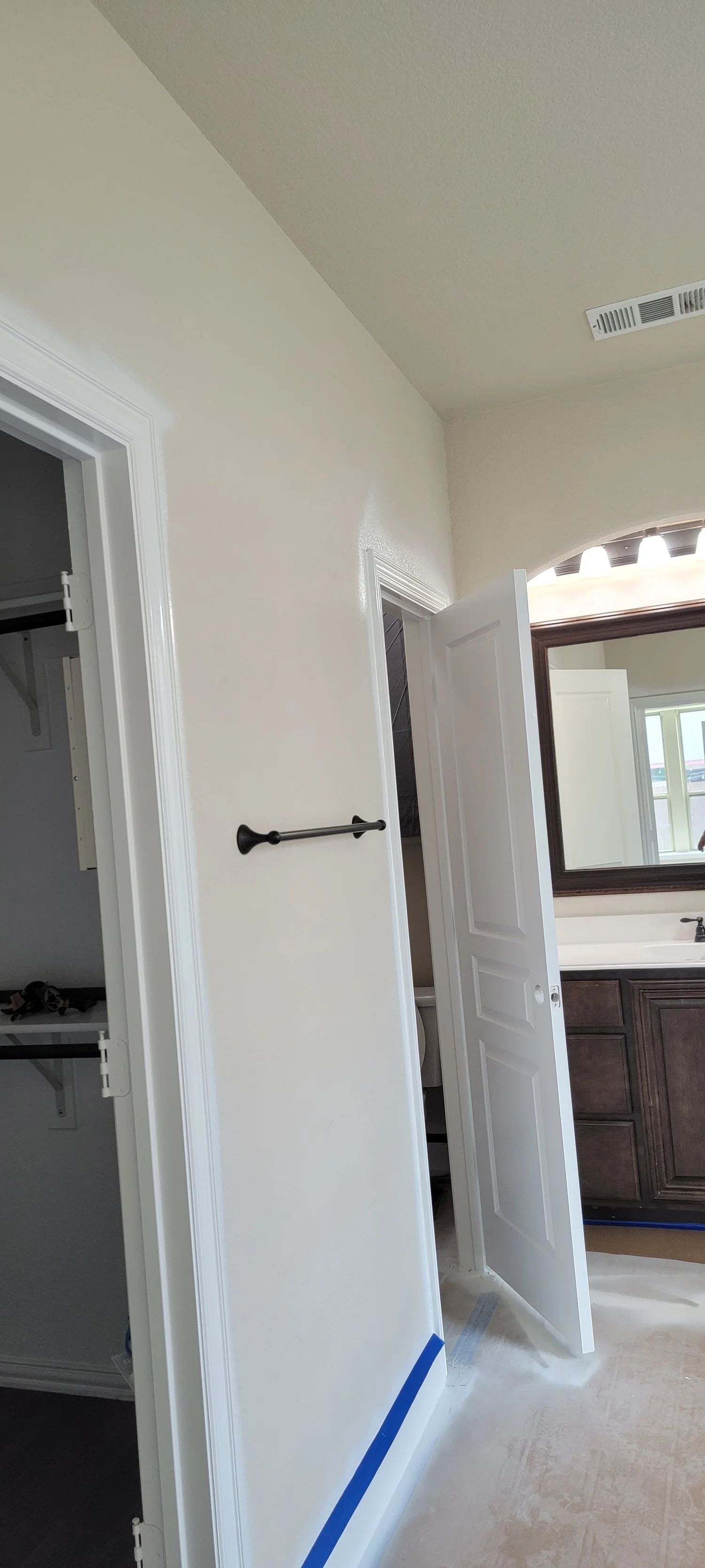 A white door, partially open in a room with a towel rack and a closet opening.