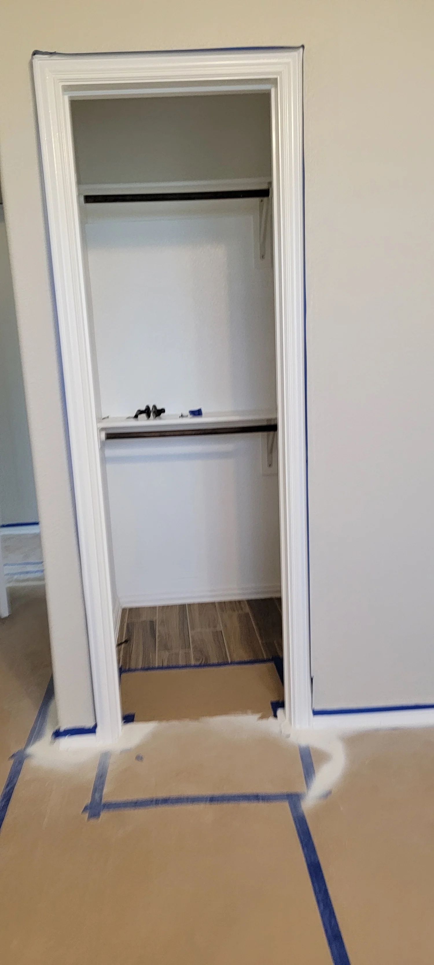 Closet doorway with white trim and a brown floor. Paint lines are visible on the surrounding walls and floor.