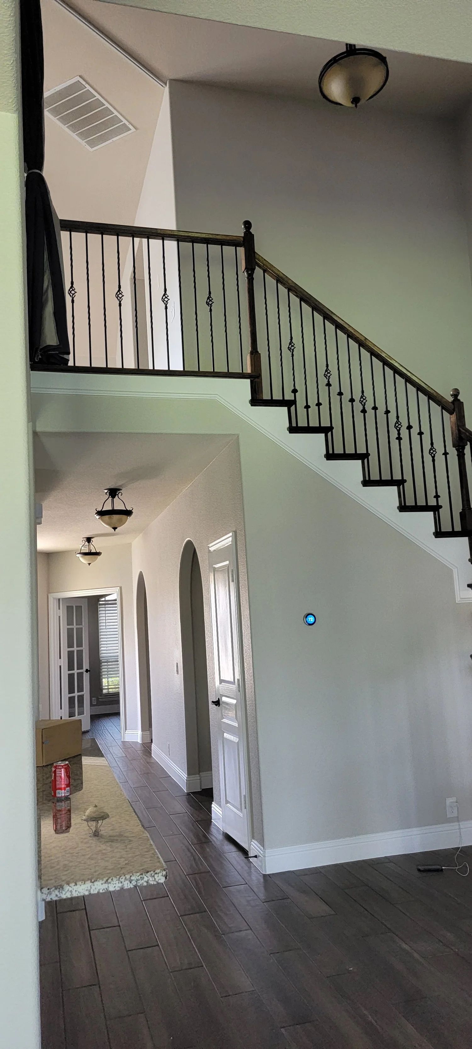 Interior view of a house with a staircase, hallway, and dark wood flooring. The walls are gray.