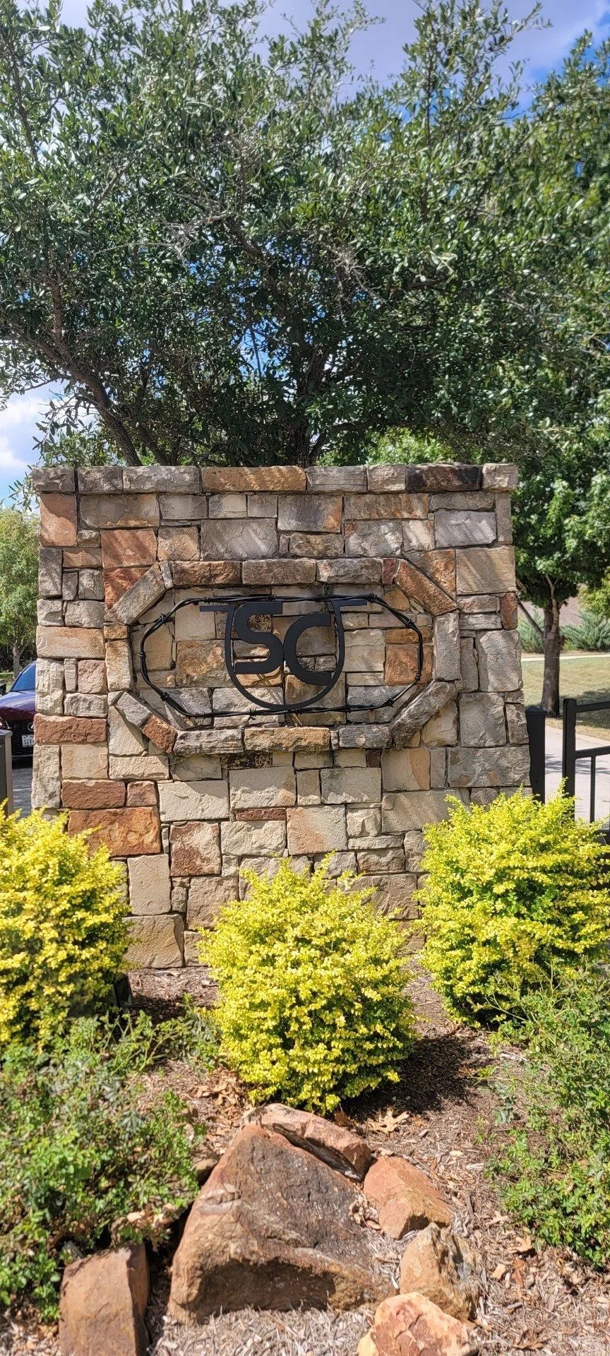 Stone entrance to a property with metal emblem featuring the letters 