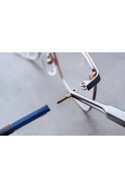 Hands using pliers to cut a small metal wire on a bicycle wheel.