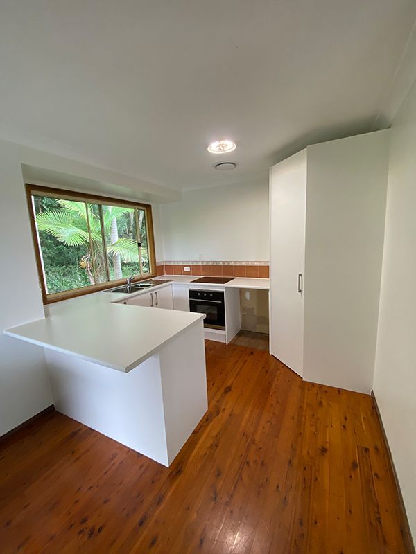 A Kitchen With Wooden Floors, White Cabinets And A Large Window — Cut N Edge Panel Factory In Coolum Beach, QLD