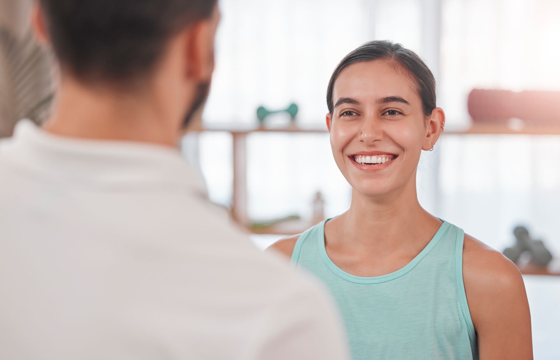 A woman is smiling while talking to a man in a gym.