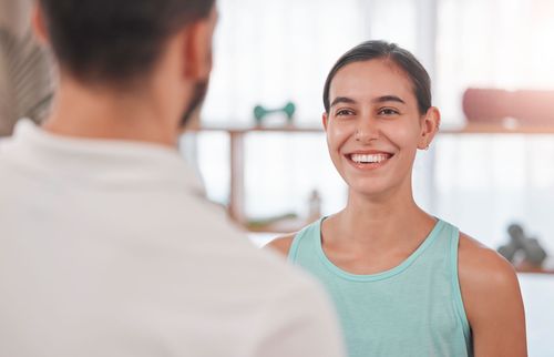 A woman is smiling while talking to a man in a gym.