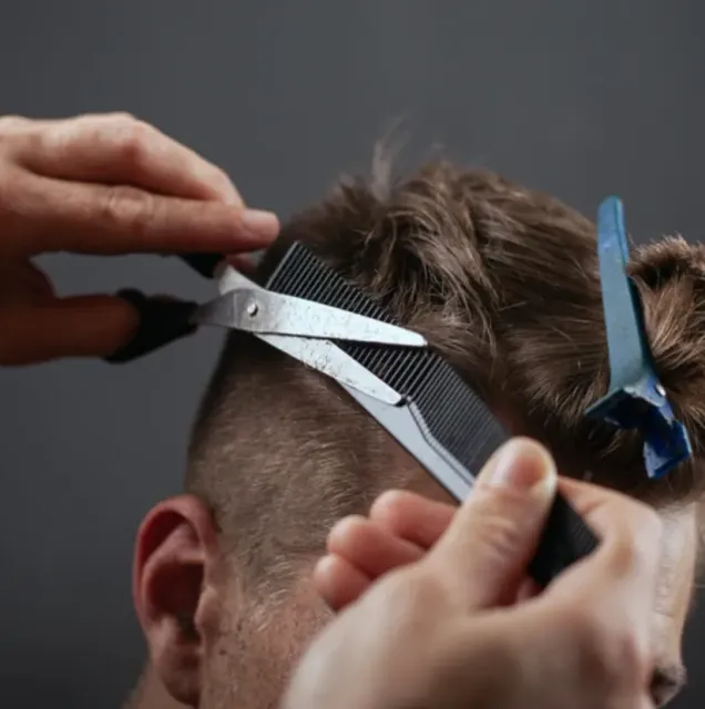 a man is getting his hair cut with scissors and a comb