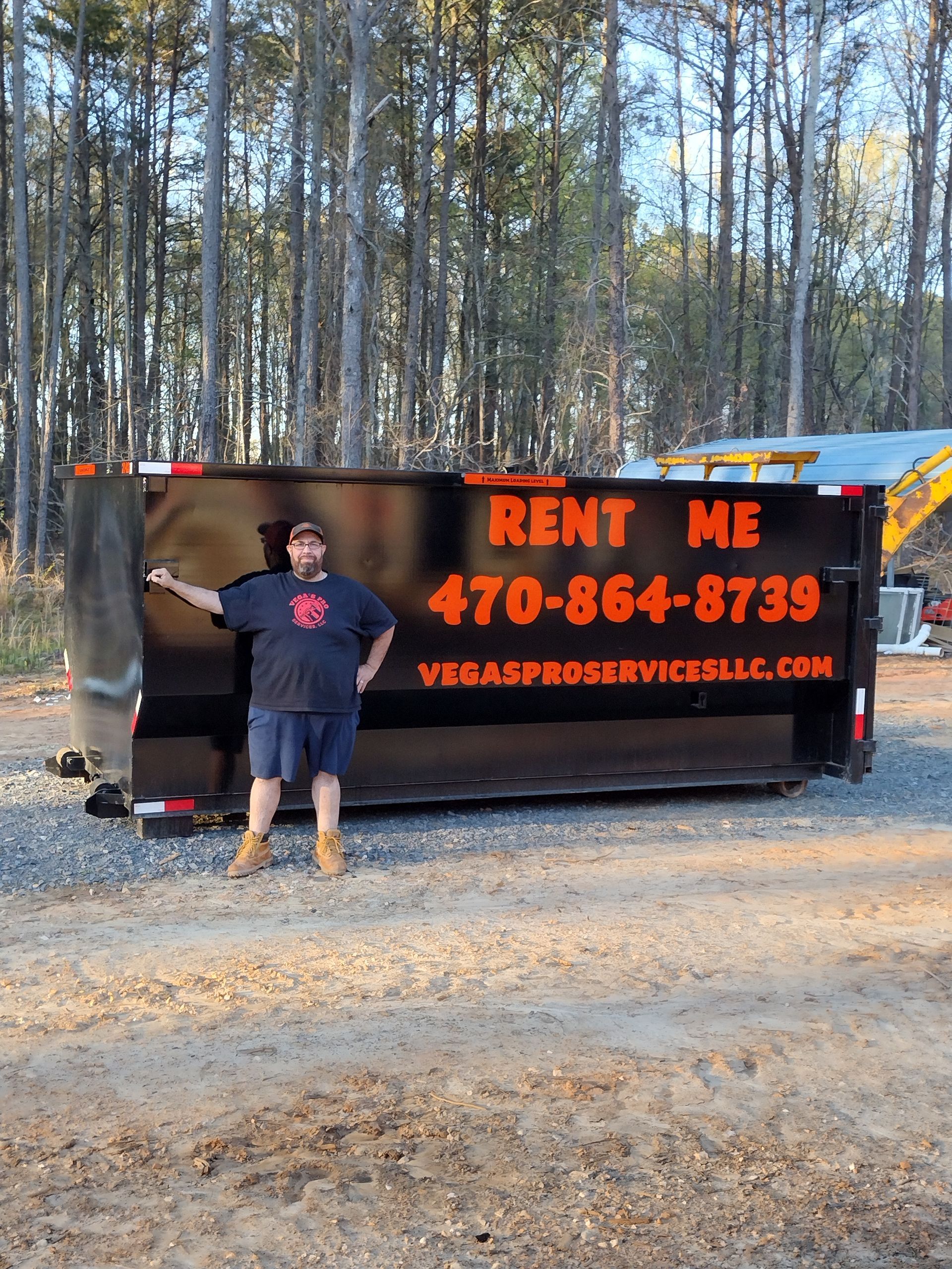 Man standing next to a black dumpster, advertising