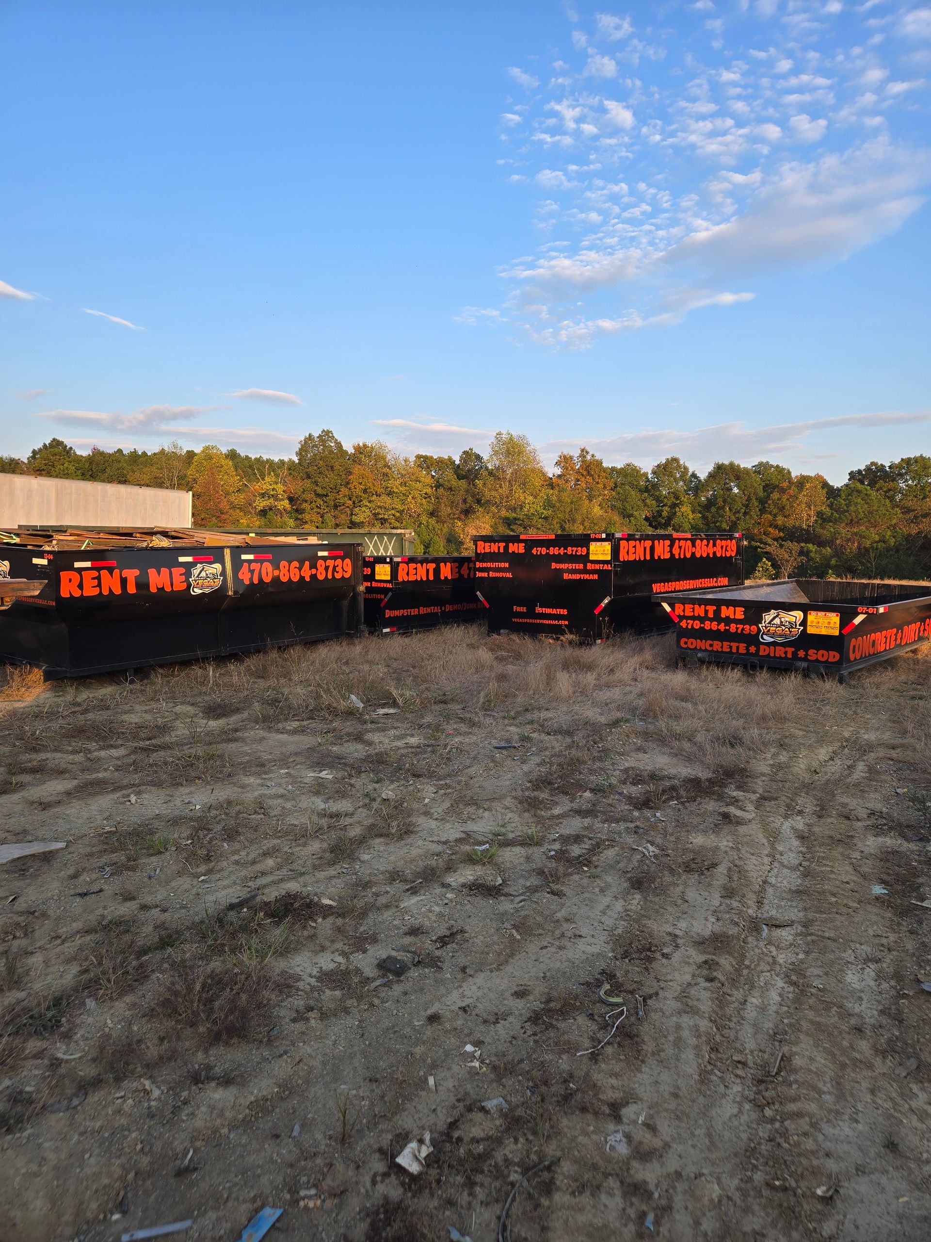 Orange and black storage containers stacked outdoors under a blue sky. Trees and a building are in the background.