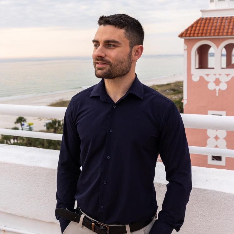 A man with a beard is wearing a blue suit and white shirt