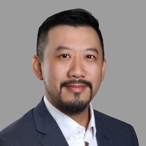 A man with a beard is wearing a suit and white shirt.