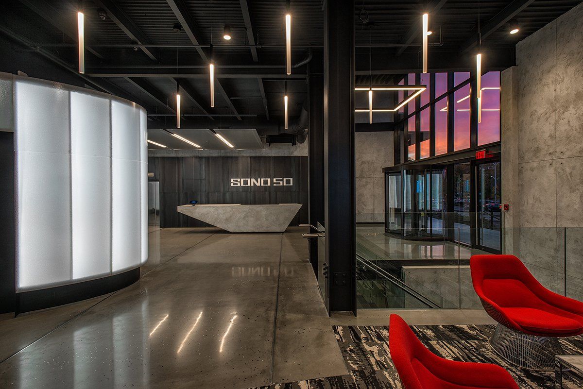 There are two red chairs in the lobby of a building.