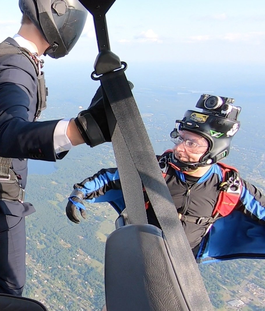 A man in a suit is helping another man in a parachute.