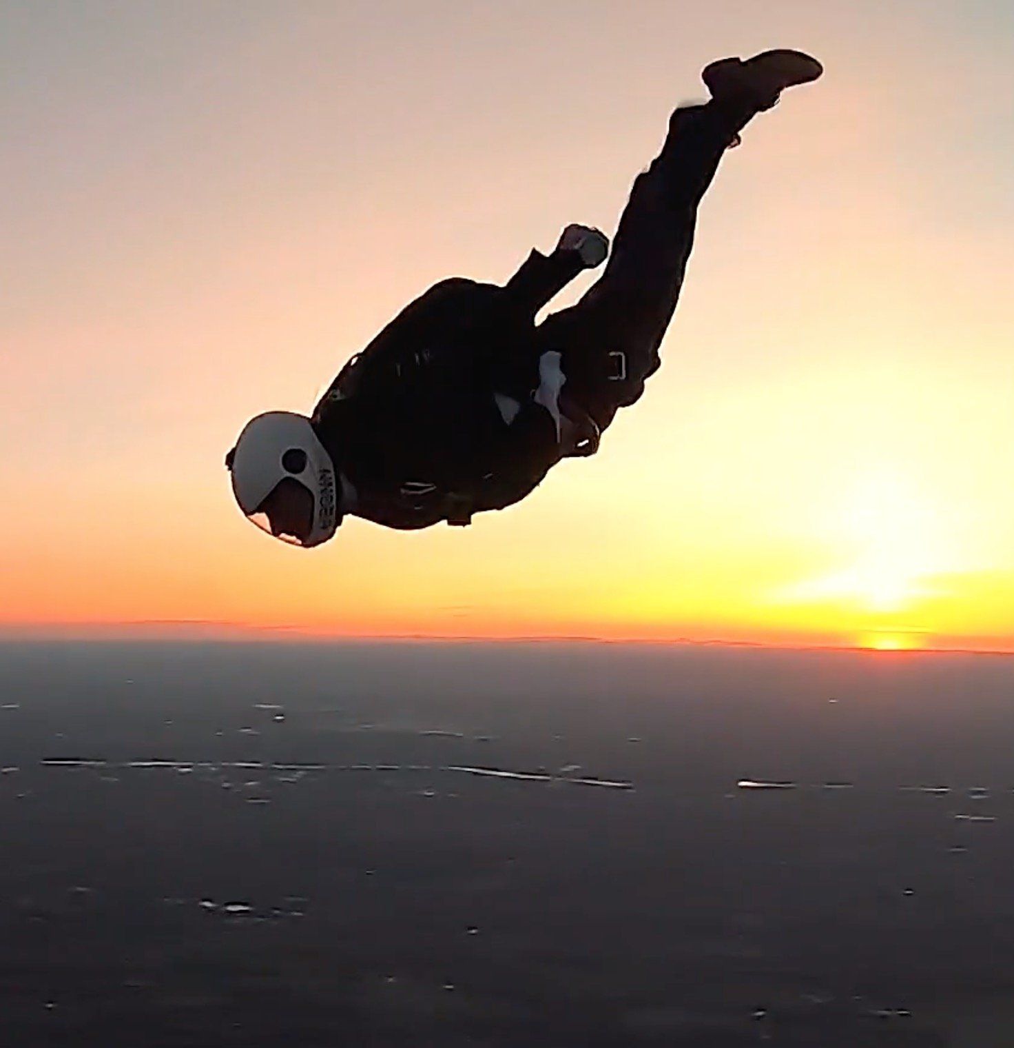 A person is flying through the air at sunset