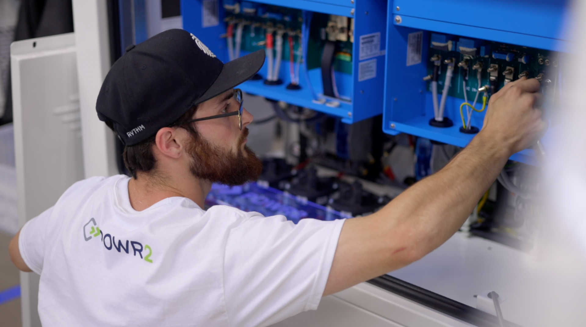 A man wearing a hat and glasses is working on a machine.