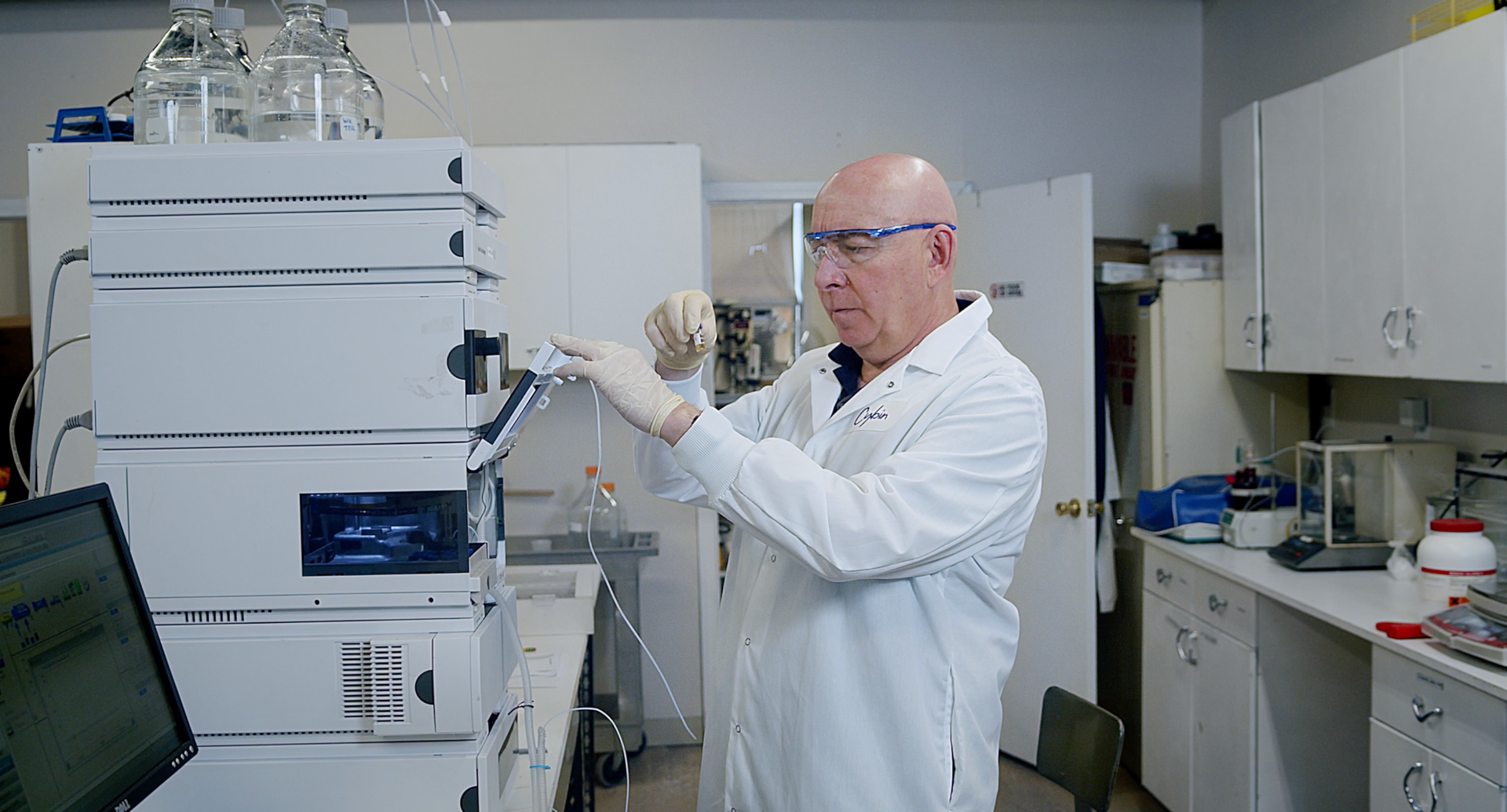A man in a lab coat is working on a machine in a laboratory.
